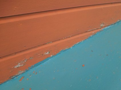 外壁の下屋根の取り合い部が密着しているため、水の吸い上げによる塗膜剥離が確認できます。